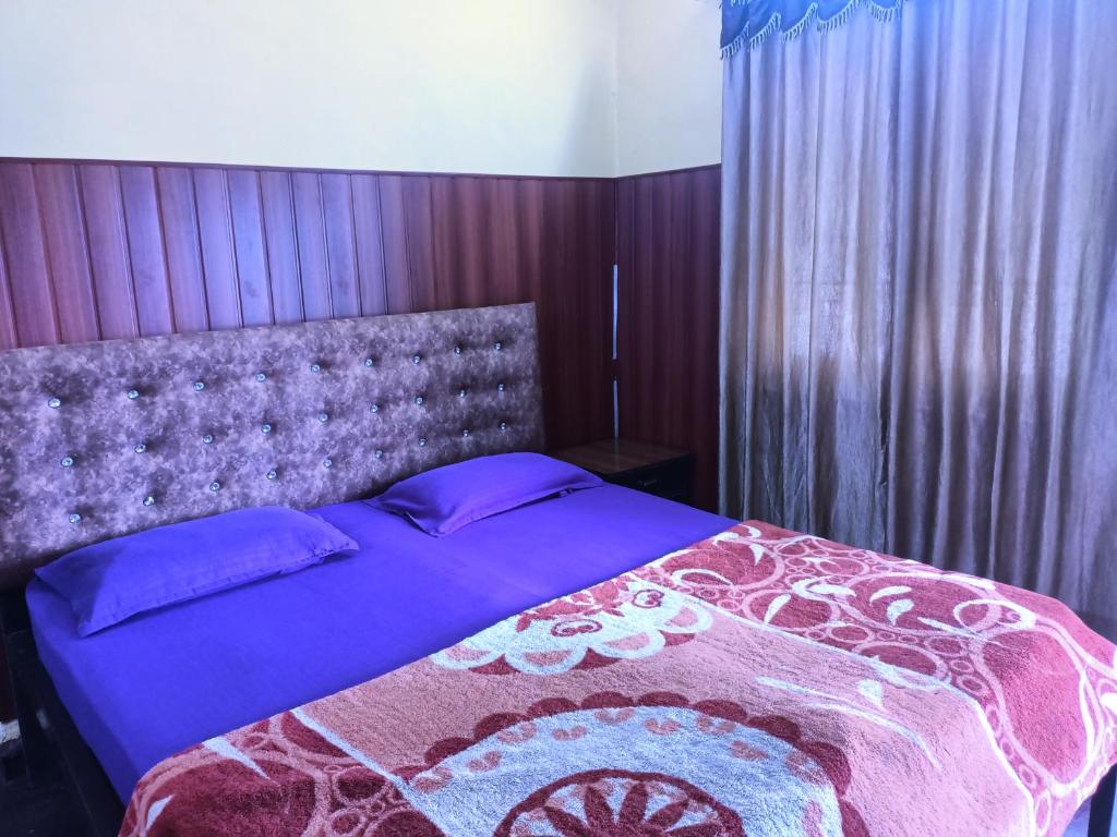 a bedroom with a bed with a purple comforter at Adrose Cotttages & Family Restaurant Colva in Colva