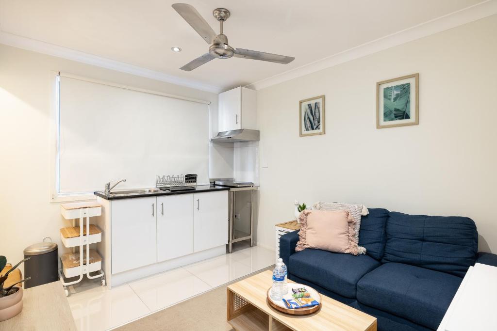 a living room with a blue couch and a kitchen at Great Location! Close to Restaurants & Train! in Brisbane