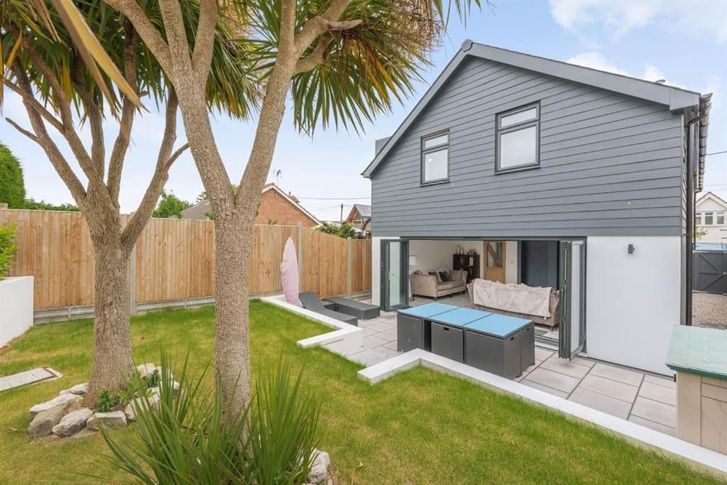 a backyard with a house with a table and palm trees at The Beach Hut in Seasalter