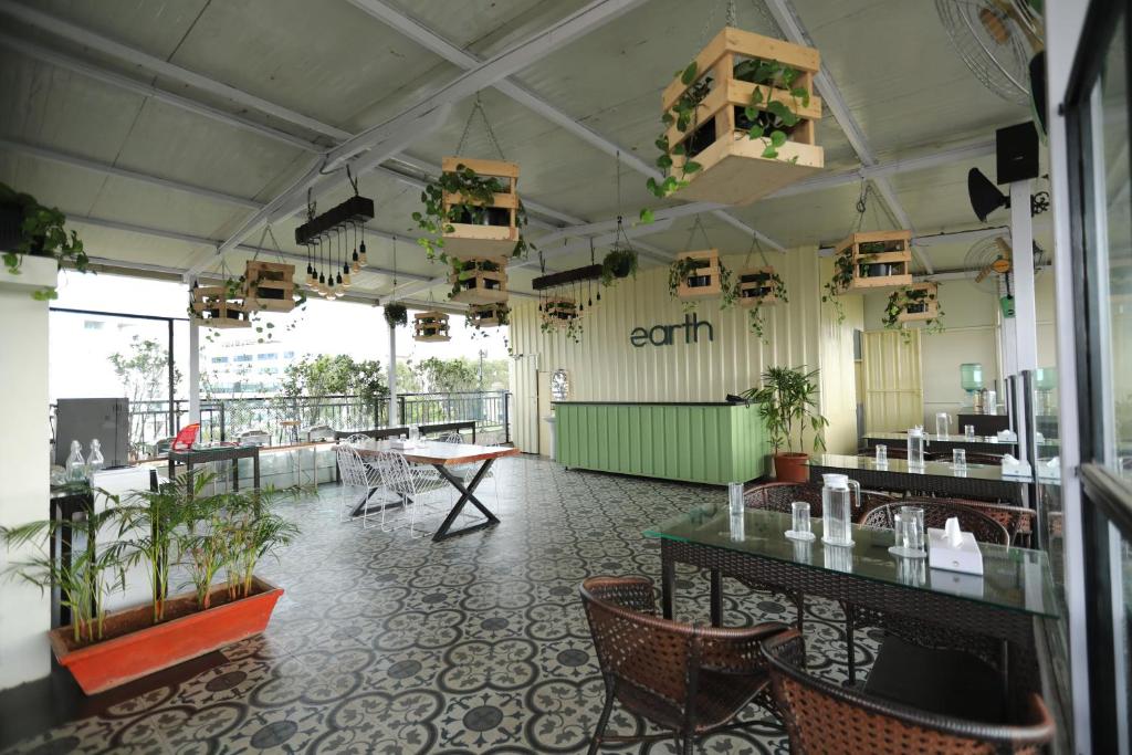 een restaurant met tafels en stoelen en planten aan het plafond bij Earth Hotels in Bangalore