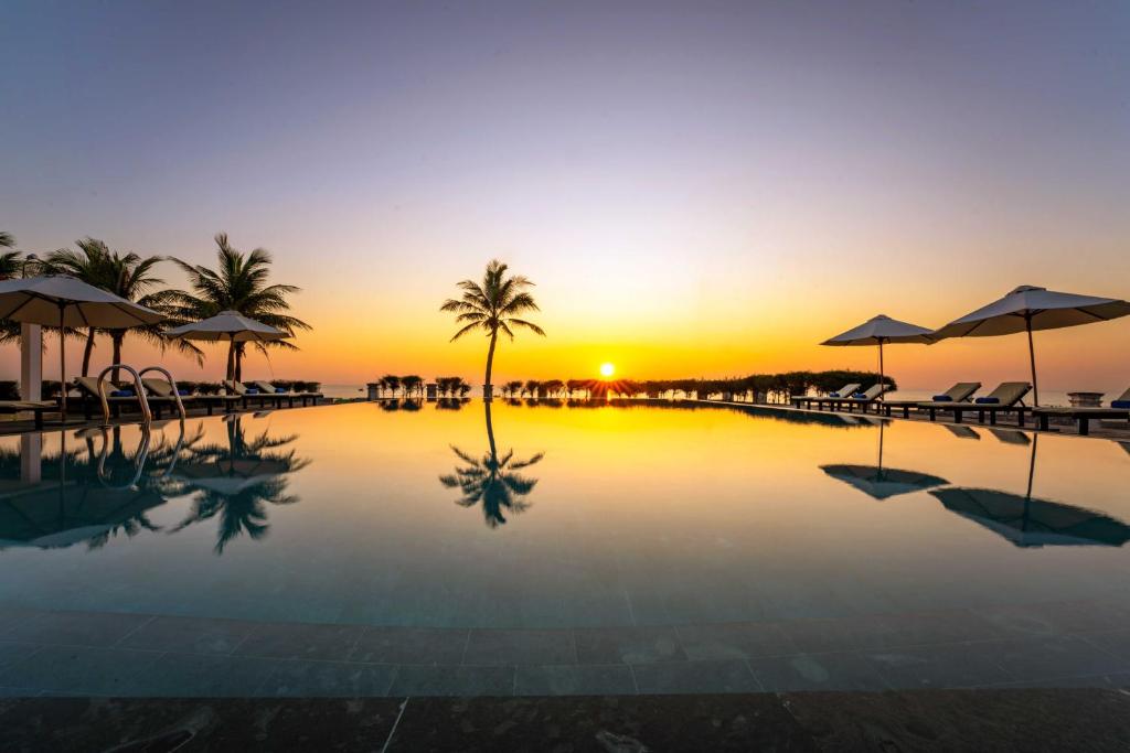 uma piscina com um pôr-do-sol ao fundo em Tam Thanh Beach Resort & Spa em Tam Kỳ