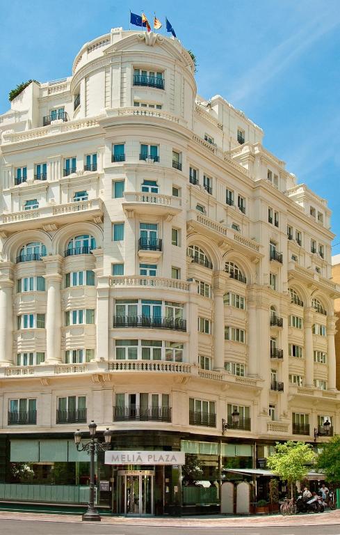 a large white building with a flag on top of it at Melia Plaza Valencia in Valencia