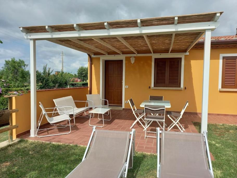 een patio met stoelen, een tafel en een luifel bij Monolocale in campagna vicino Bolgheri e mare in Cecina