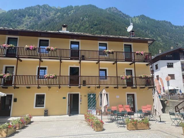 a large yellow building with a balcony with tables and chairs at Hotel SALEI in Ghigo