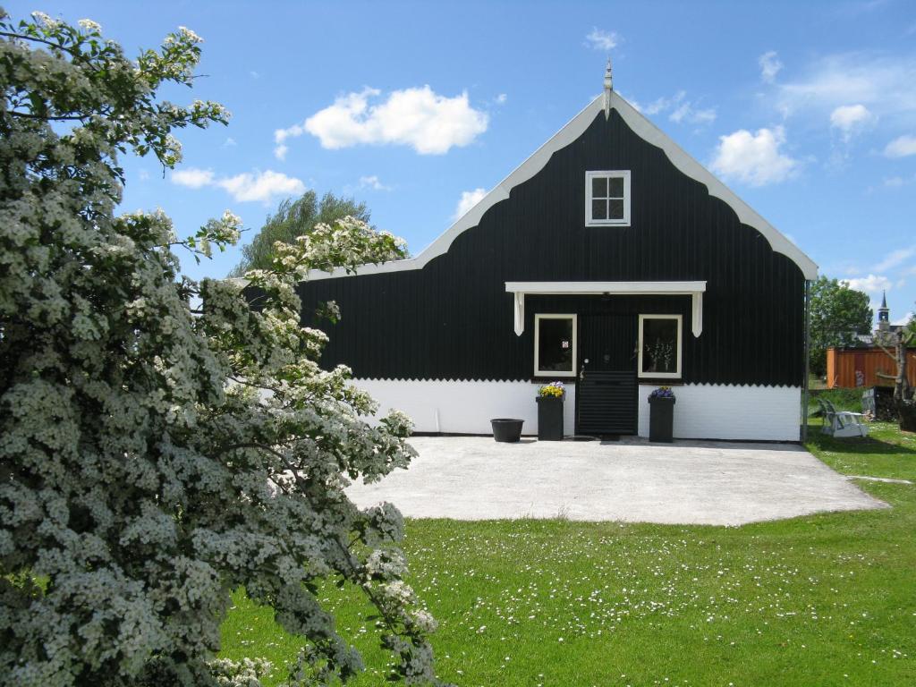 um celeiro preto e branco com uma cruz no telhado em vakantiehuis Warder em Warder