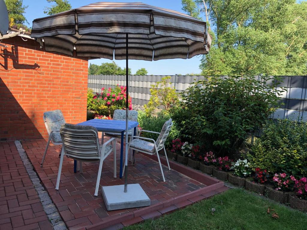 einen Tisch und Stühle unter einem Sonnenschirm auf einer Terrasse in der Unterkunft Haus Ahkamp in Hemmoor
