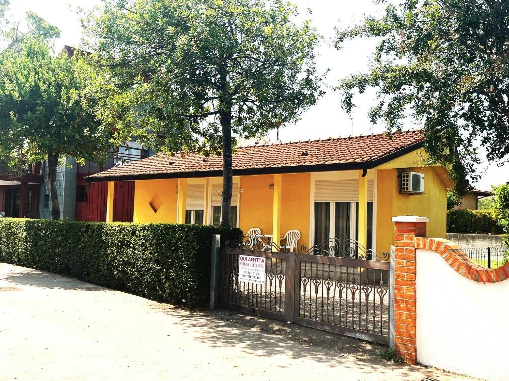 a yellow house with a fence in front of it at villa Sayonara in Lignano Sabbiadoro