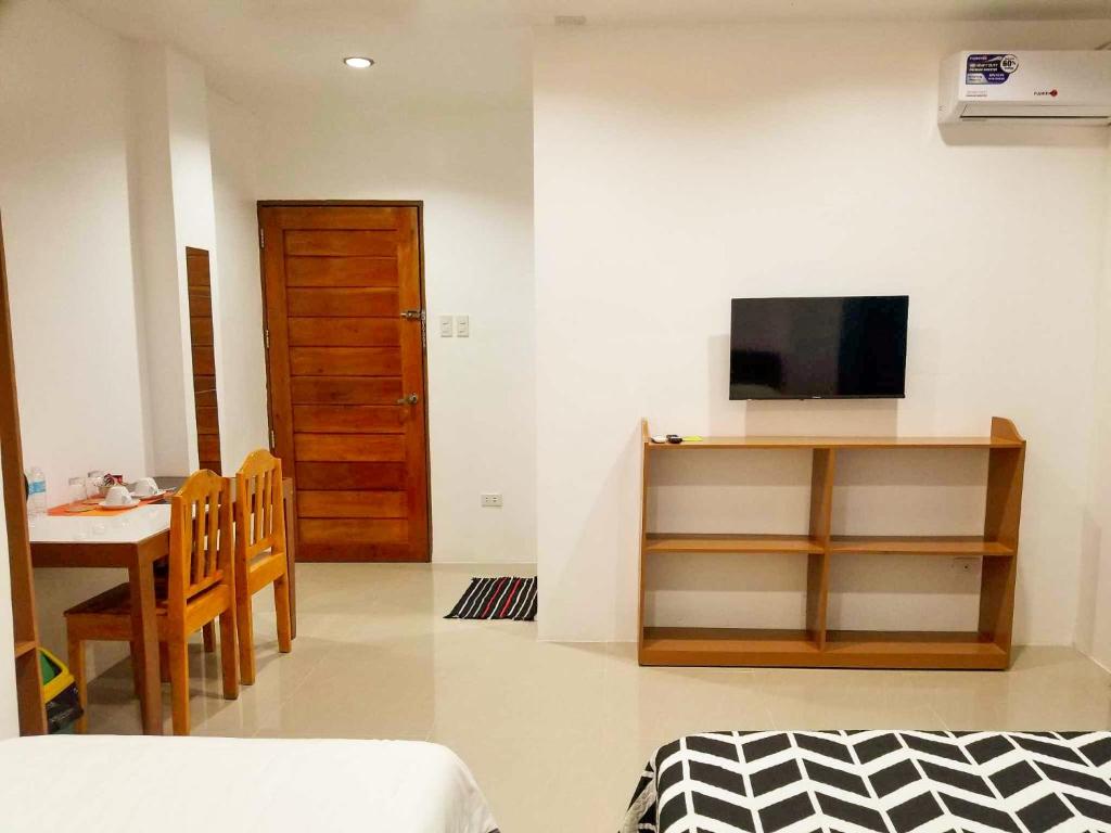 ein Wohnzimmer mit einem Tisch und einem TV sowie ein Zimmer in der Unterkunft Majestique Hotel Albay Bicol in Guinobatan