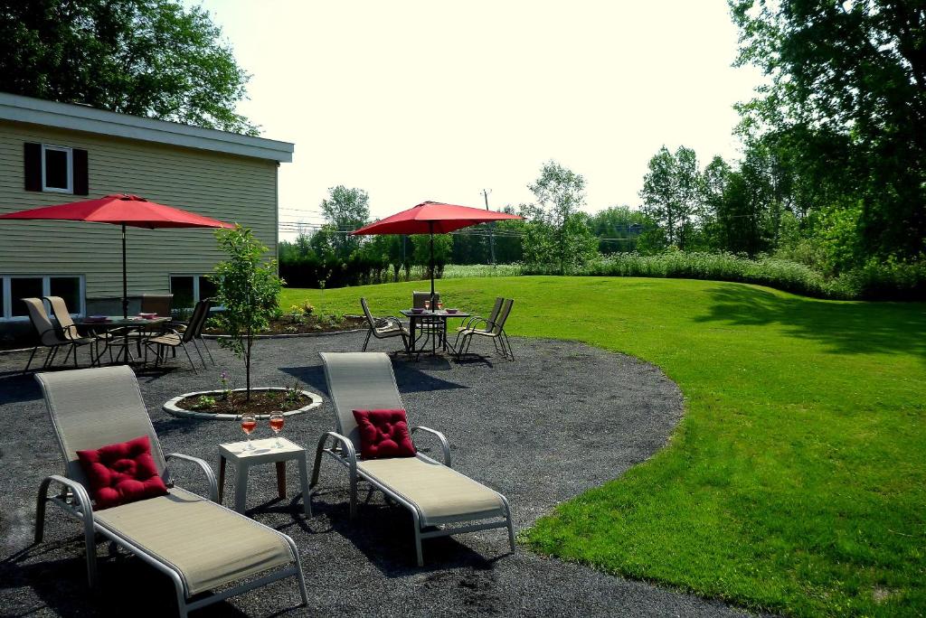 a patio with tables and chairs and a table with red pillows at Hôtel-Auberge Objectif Santé in Longueuil