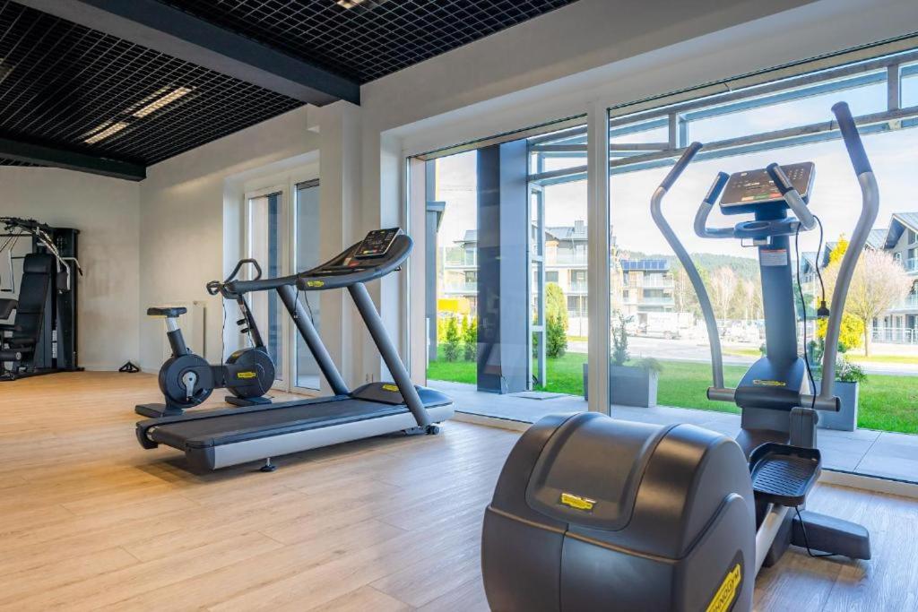 a gym with two tread machines in a room with a large window at Apartament Bosko przy Jeziorze Żywieckim Laguna Beskidów in Łodygowice