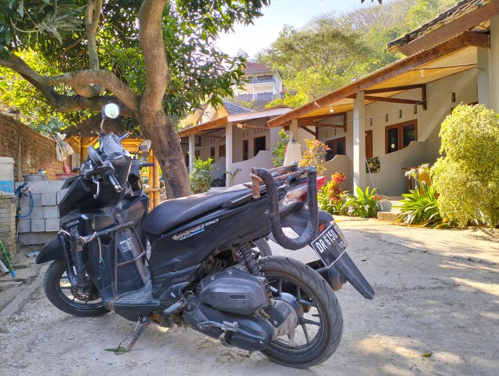 a black motorcycle parked in front of a house at T&T Homestay in Kuta Lombok