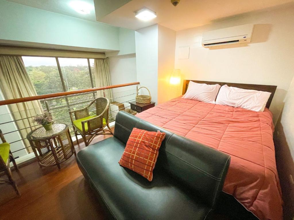 a bedroom with a bed and a couch and a balcony at Lovely 1BR Loft in BGC up to 6pax in Manila