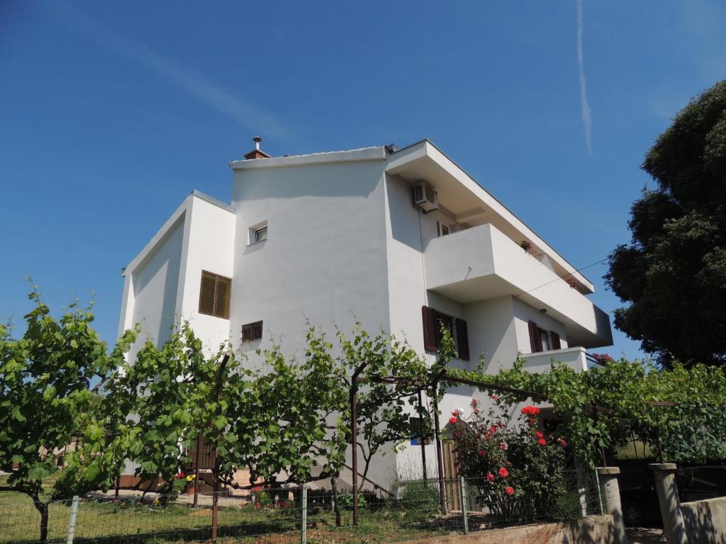 a white building with a fence in front of it at Apartments Dolac in Sveti Filip i Jakov