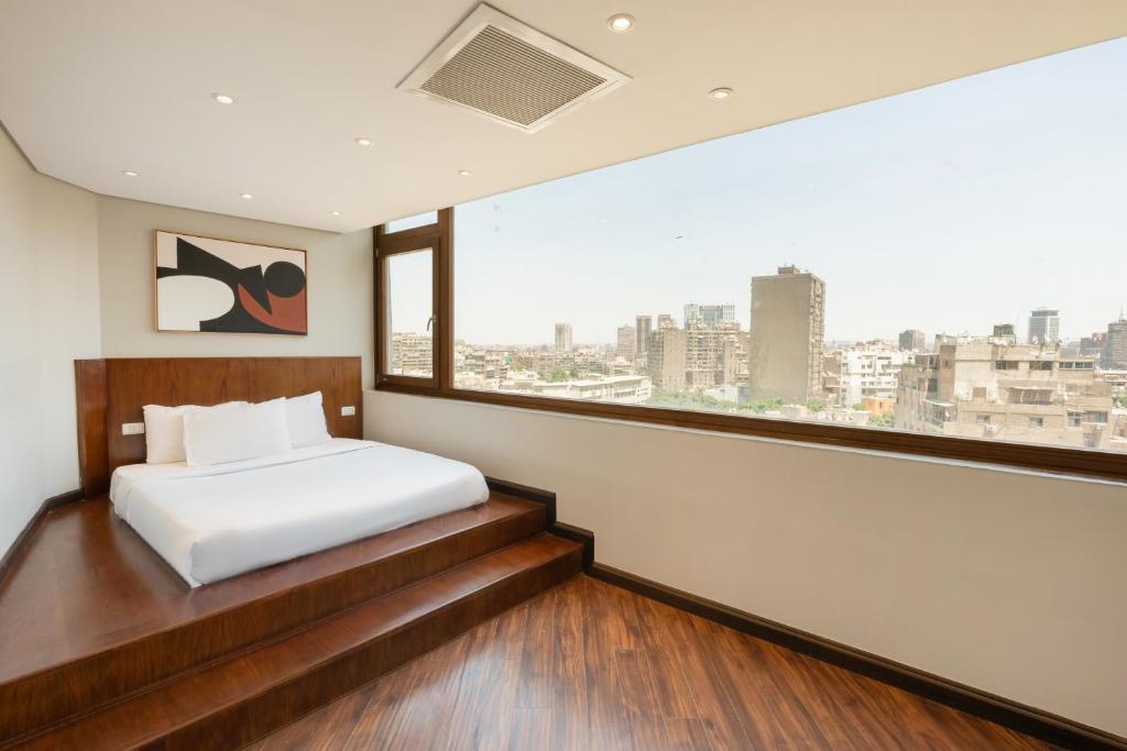 a bedroom with a white bed and a large window at Zamalek Serviced Apartments by Brassbell in Cairo