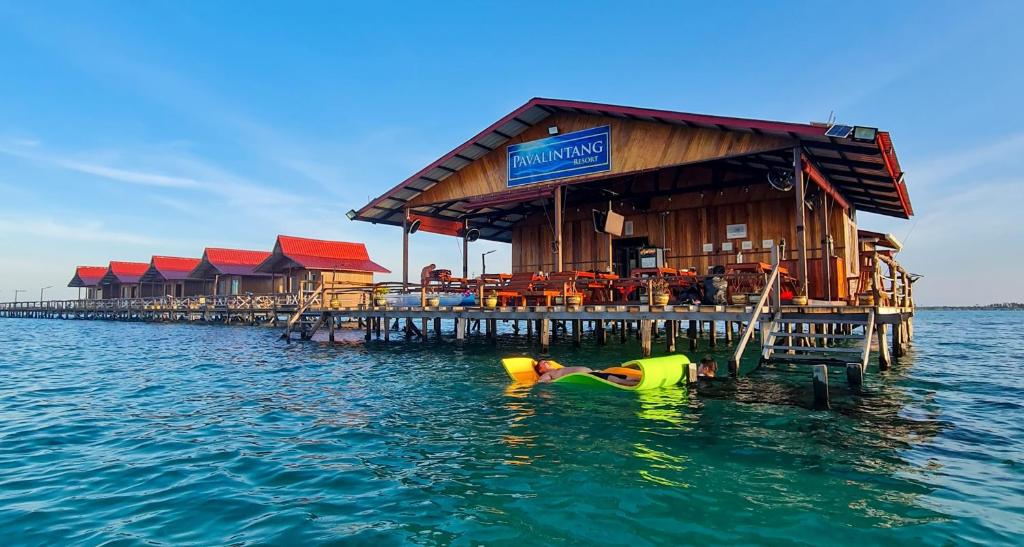 a person in the water in front of a restaurant on a pier at Pavalintang Resort in Semporna