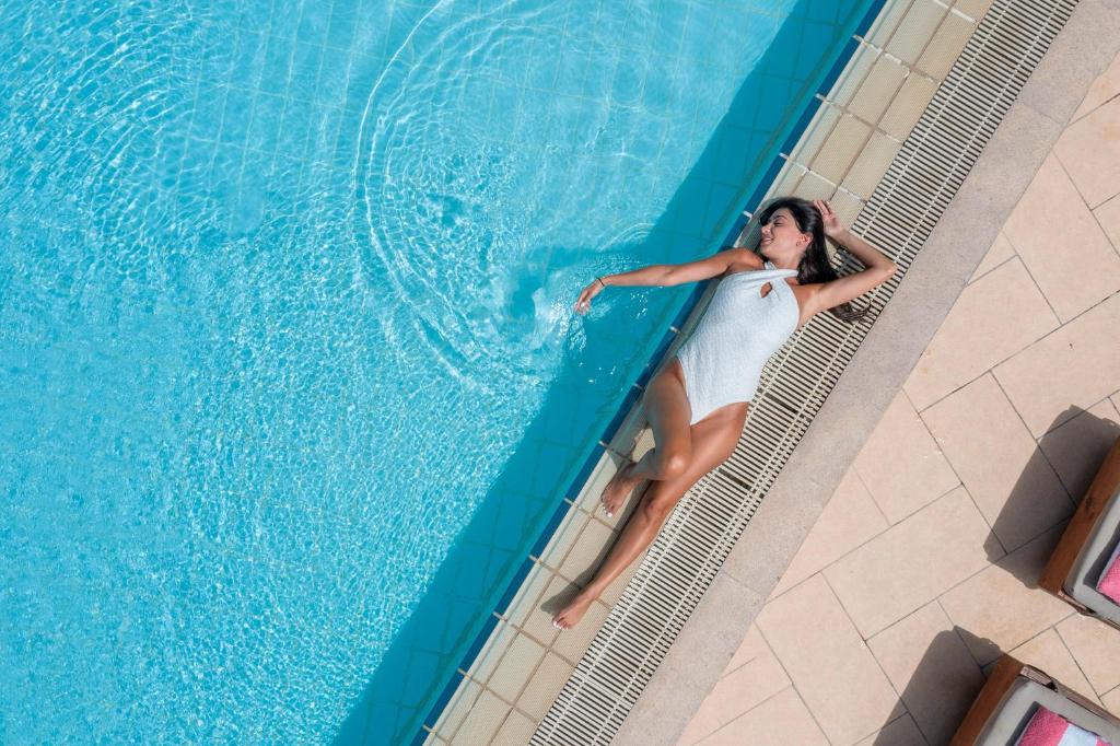 a woman in a white dress standing in a swimming pool at St Raphael Resort in Limassol