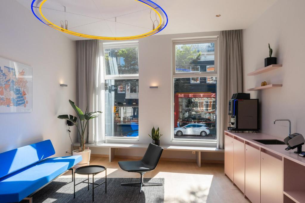 171. Urban Design Hotel في روتردام: مطبخ وغرفة معيشة مع أريكة وكراسي زرقاء