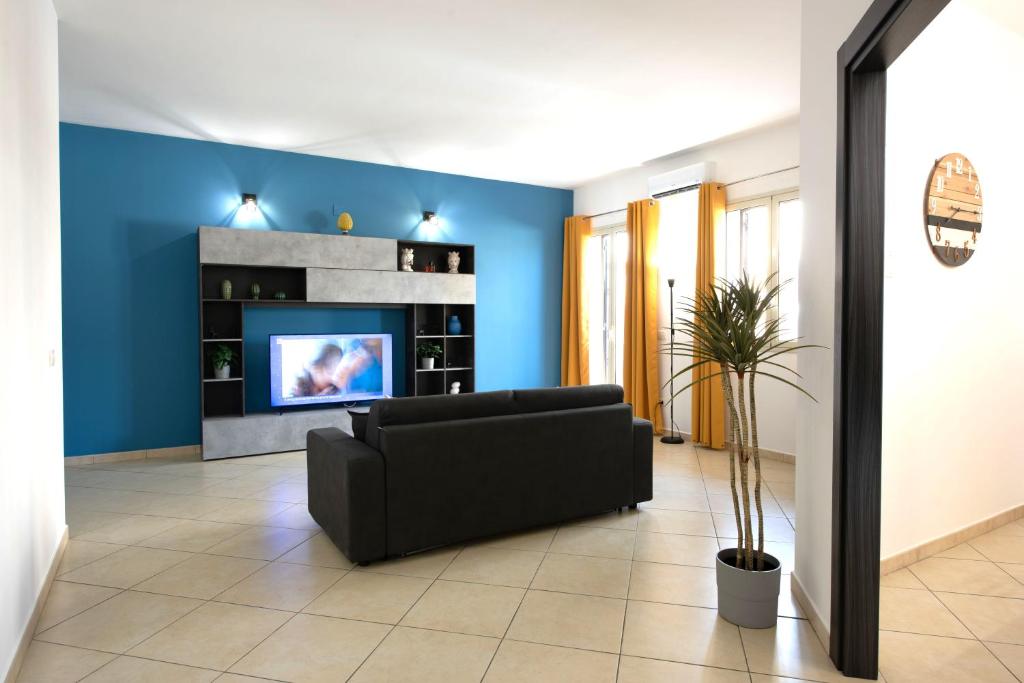 sala de estar con sofá negro y TV en Casa vacanza Luna, en Cassibile