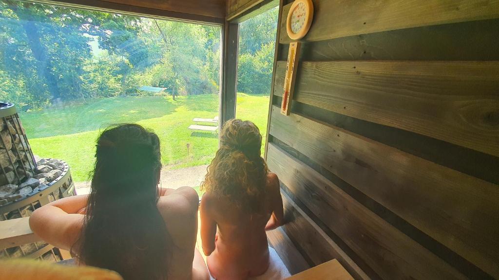 Dos chicas mirando por una ventana en una cabaña en B&B Naturista e Spa Mondoselvaggio, en Lucca
