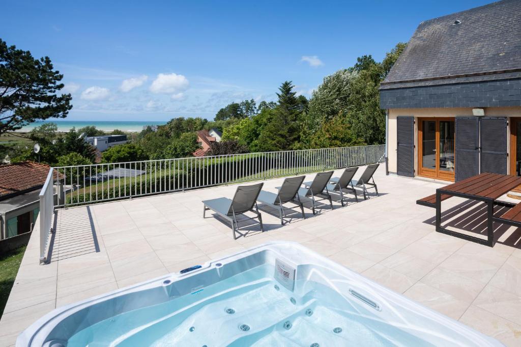 uma banheira de hidromassagem num pátio com cadeiras e uma mesa em La Villa Maxine, vue mer et spa em Criel-sur-Mer