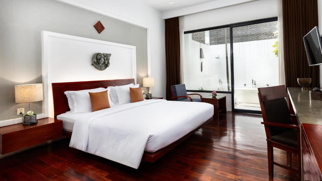a bedroom with a large white bed and a large window at Lynnaya Urban River Resort in Siem Reap