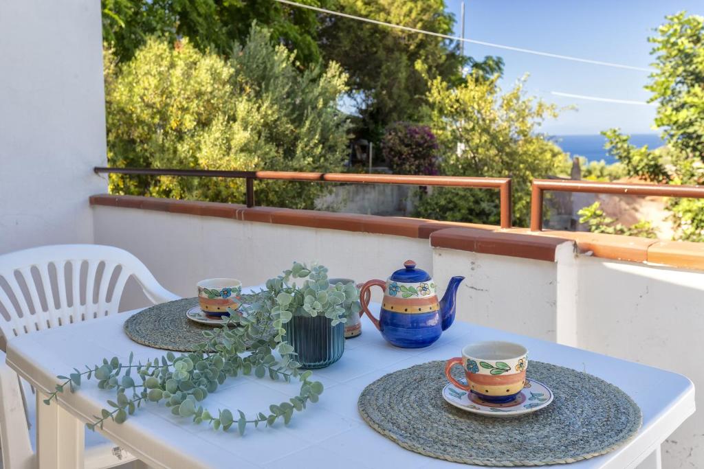 een tafel met twee kopjes en schotels op een balkon bij Casa Pisaro Lu Bagnu in Castelsardo