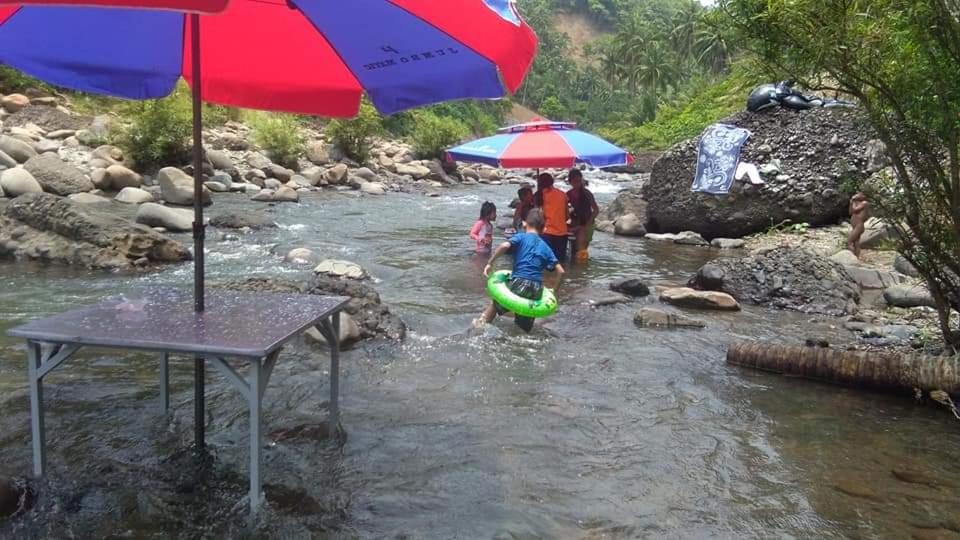 eine Gruppe von Menschen, die in einem Fluss mit Sonnenschirmen stehen in der Unterkunft Iluv layun in Real