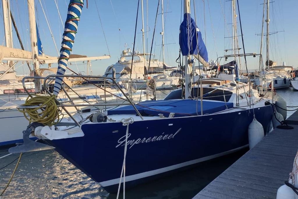 een blauwe boot aangemeerd aan een steiger met andere boten bij Vacations in a Sailboat in Lissabon