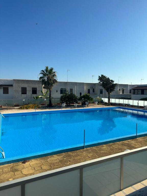 Una gran piscina azul frente a un edificio en CASA APPRODO, en Porto Cesareo