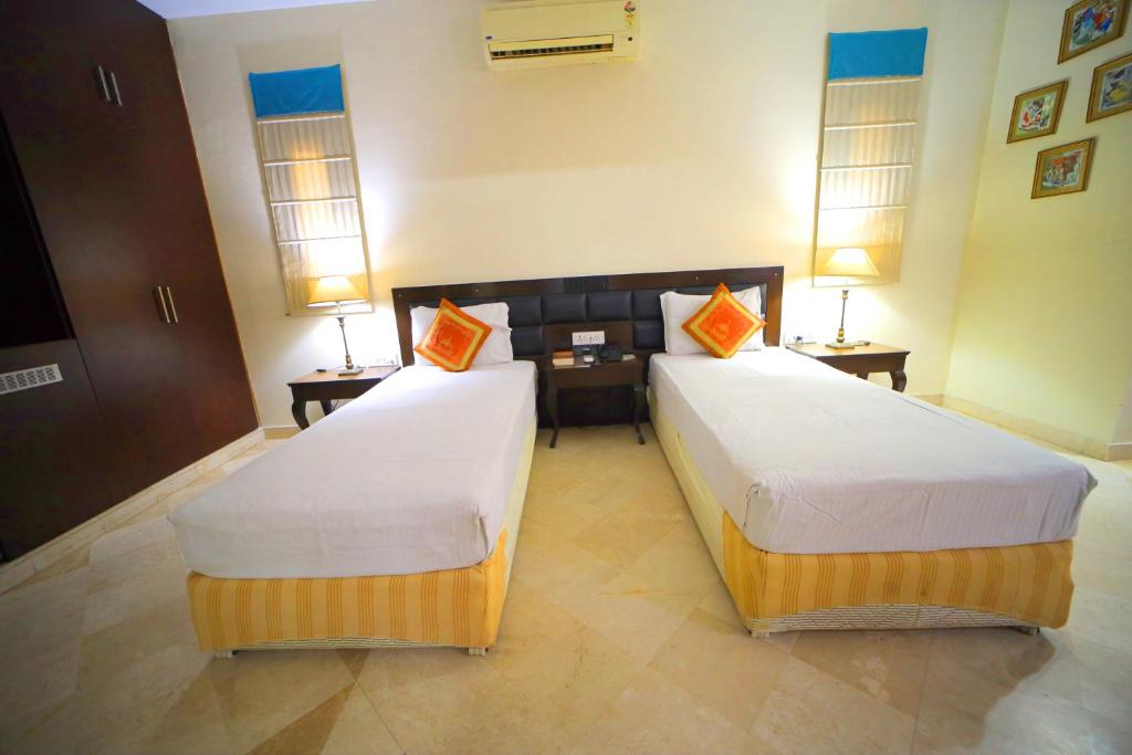 Bansi Home Stay في آغْرا: غرفة بسريرين وطاولتين ومصباحين