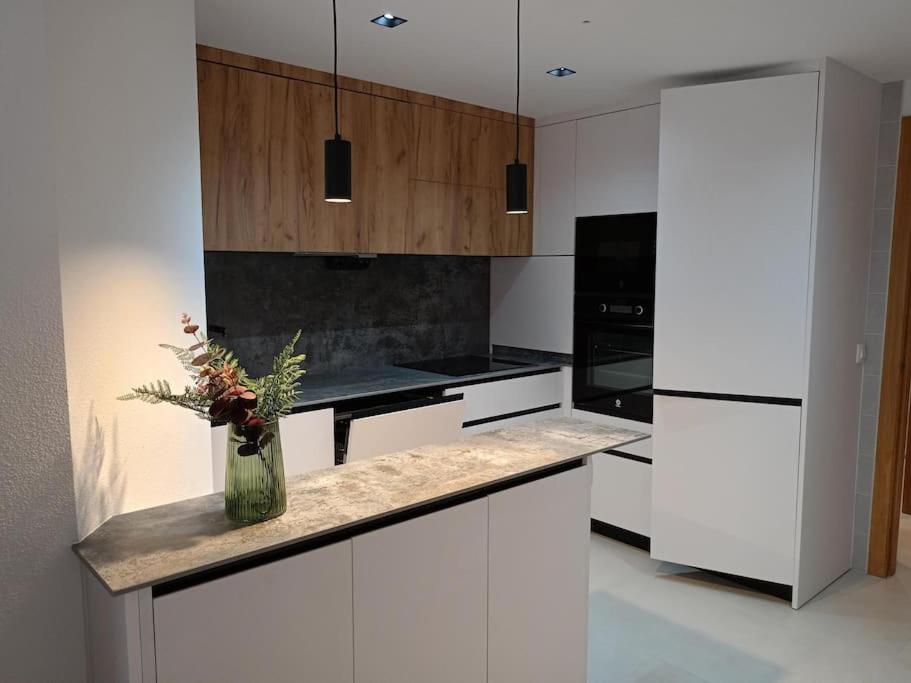 eine Küche mit weißen Schränken und einer Vase mit Blumen auf der Theke in der Unterkunft Apartamento 2 Dormitorios En el Centro in Alhama de Murcia