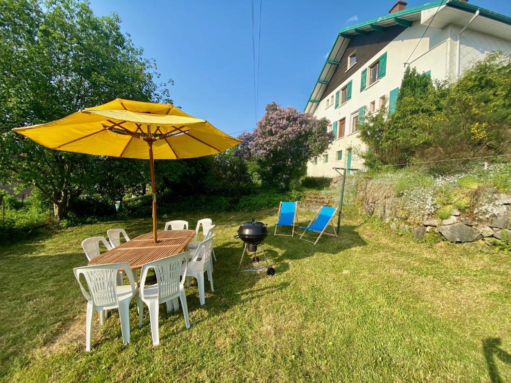 a table with a yellow umbrella and chairs and a grill at Les brimbelles in Gérardmer