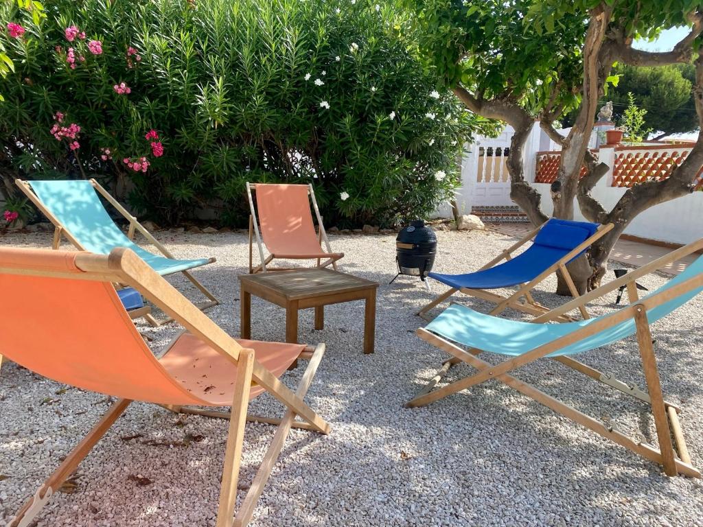a group of lawn chairs sitting next to a tree at Casa Limonero in Denia