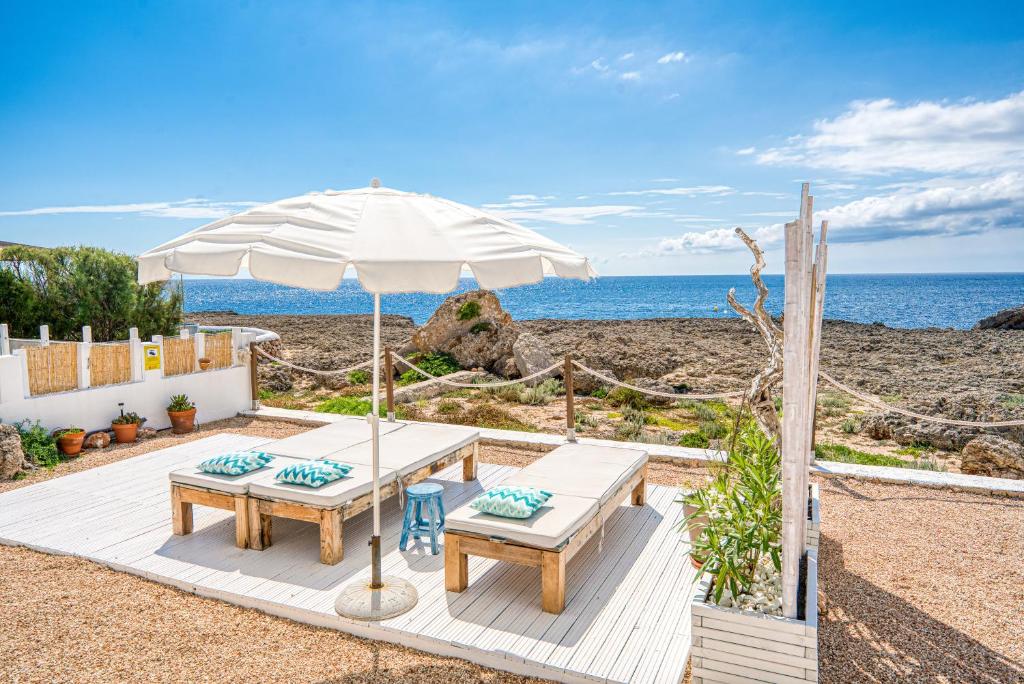 een picknicktafel en een parasol op het strand bij Mar i Vent in Cala Blanca