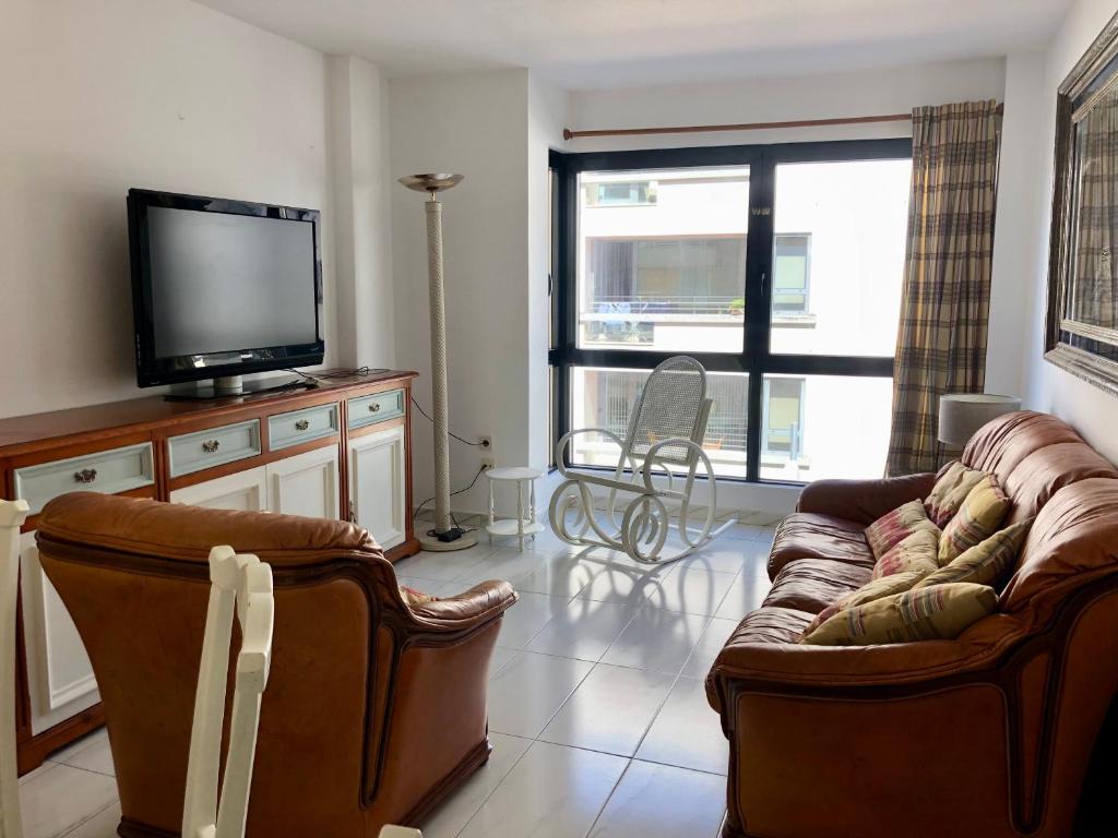 een woonkamer met een bank en een flatscreen-tv bij Apartamento céntrico en la playa de Bueu in Bueu