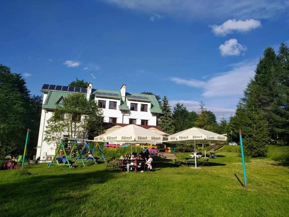 een groep mensen in het gras voor een gebouw bij Bieszczadzka Legenda in Wetlina