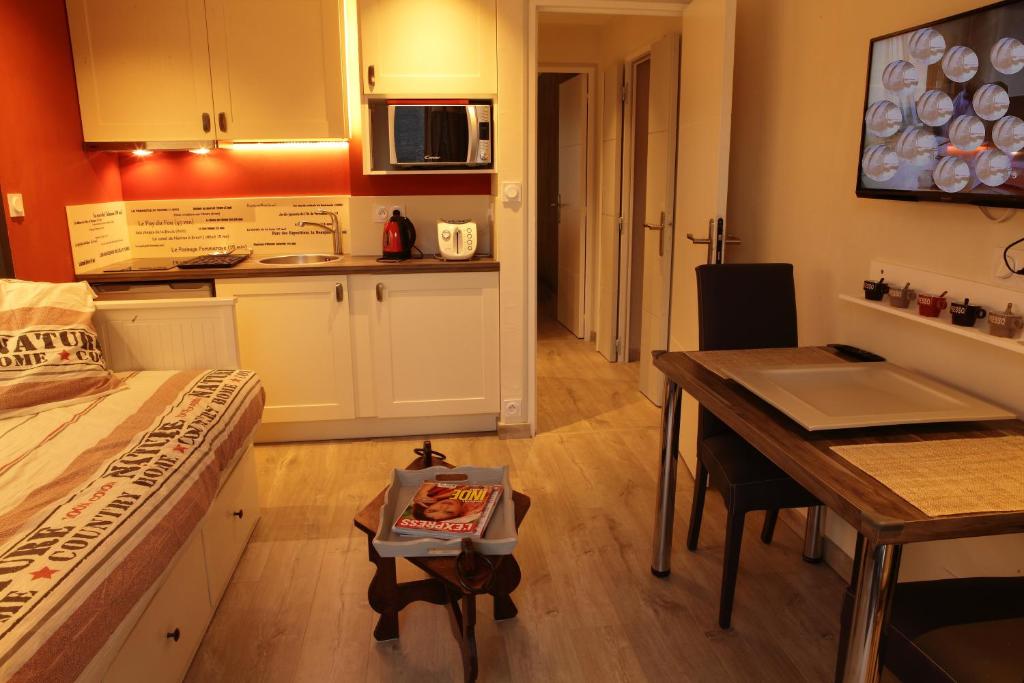 a room with a bed and a table and a kitchen at Gîte de Bonneville in Nantes