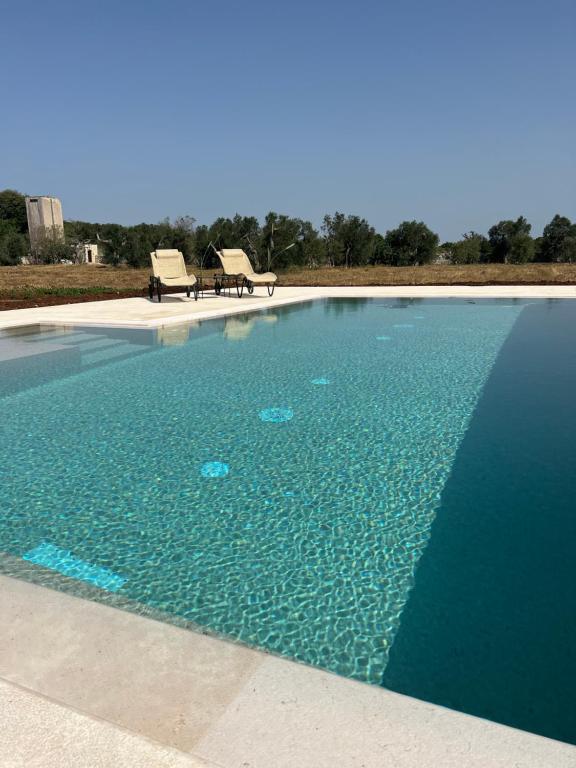 uma piscina de água com duas cadeiras em Masseria Casina Montana em Corigliano dʼOtranto