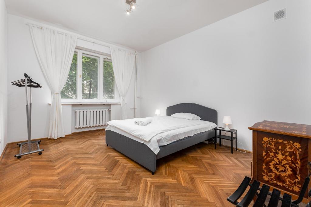 1 dormitorio blanco con 1 cama y suelo de madera en Marszałkowska 18 by Homeprime en Varsovia