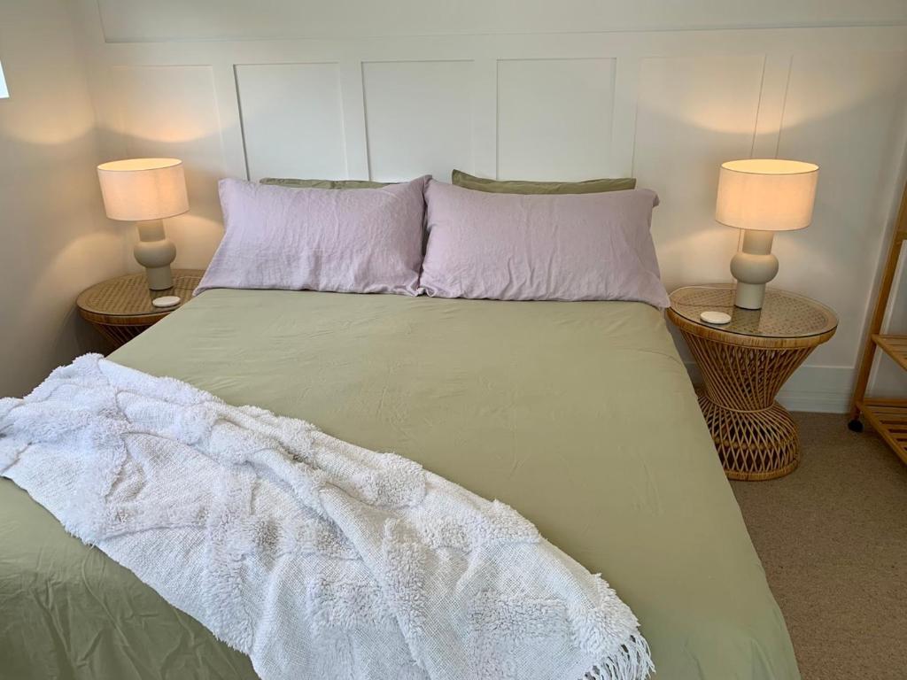 a bedroom with a large bed with two lamps at Magnolia Studio in Hastings