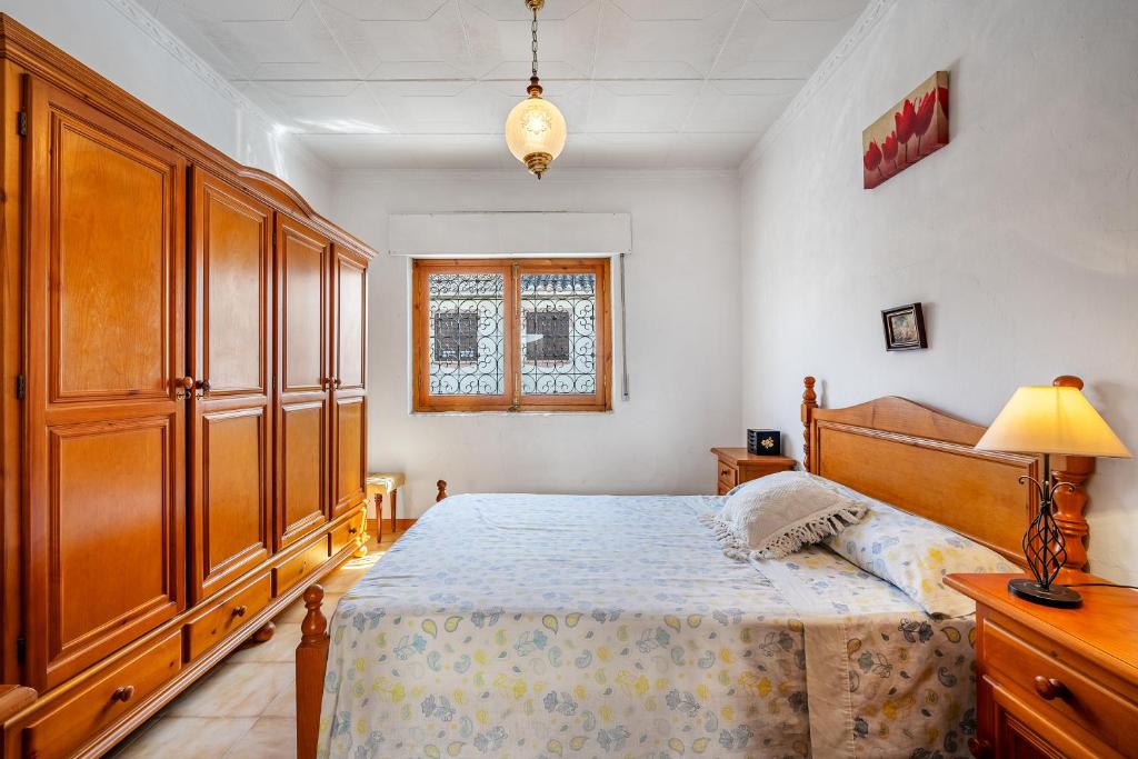 1 dormitorio con 1 cama y un gran armario de madera en Casa Solariega con encanto, en El Padul