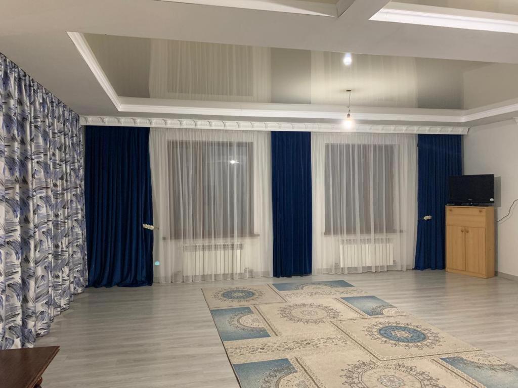 ein Wohnzimmer mit blauen Vorhängen und einem Teppich in der Unterkunft Гостевой Домик Жайлау in Taras