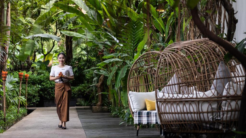 a woman walking down a walkway in a garden at Lynnaya Urban River Resort in Siem Reap