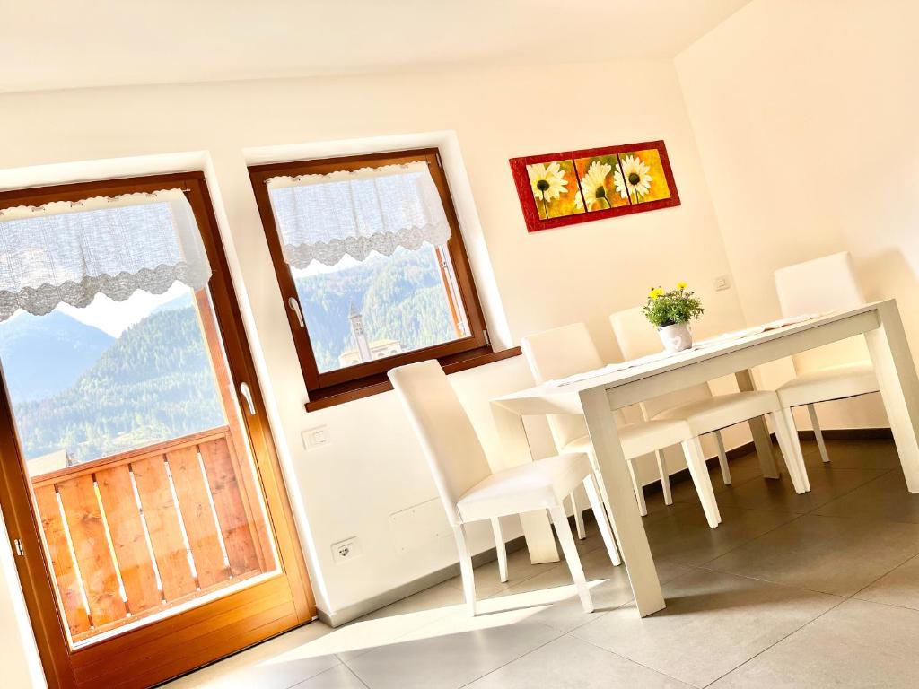 Un comedor con mesa y sillas y una ventana. en CASA MARILU', en Castello di Fiemme