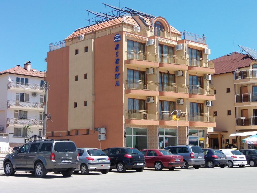 een gebouw met auto's geparkeerd op een parkeerplaats bij Hotel Sirena in Primorsko
