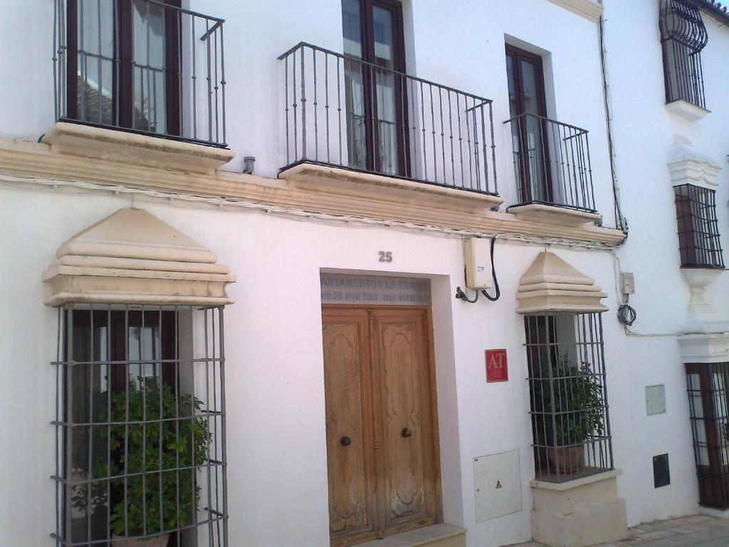 biały budynek z drewnianymi drzwiami i balkonami w obiekcie GAV La Ermita w mieście Ronda