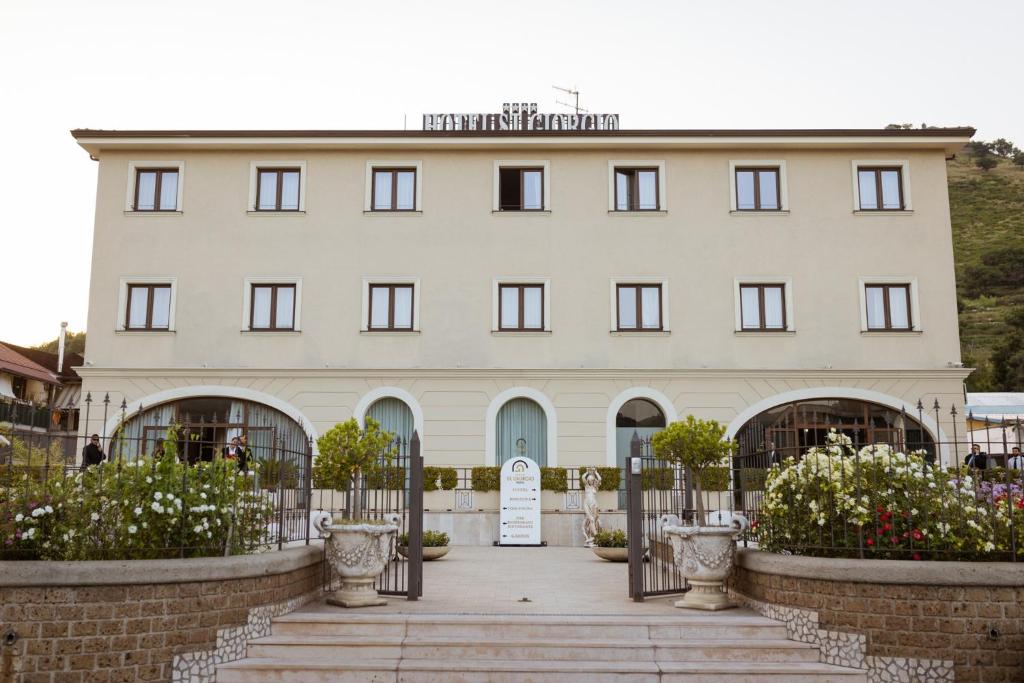 a large white building with a gate and flowers at Hotel St. Giorgio in Castel San Giorgio