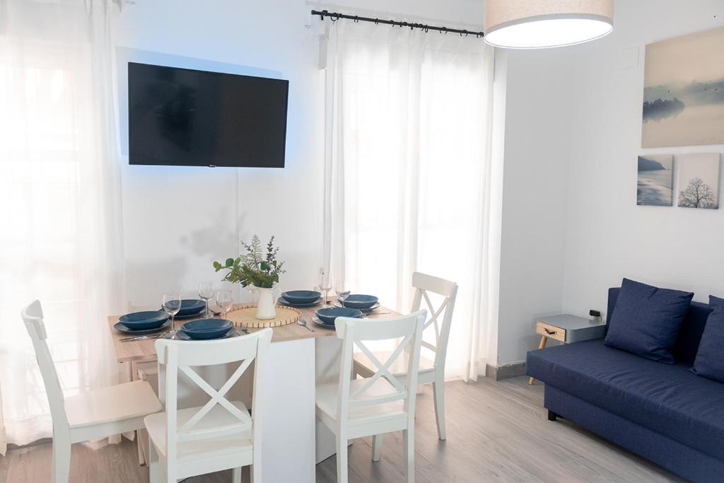une table à manger avec des chaises blanches et un canapé bleu dans l'établissement Apt. Old Town (2 bedrooms, 2 bathrooms, wifi), à Séville