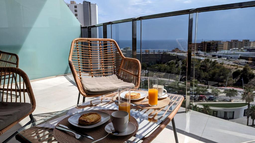 SUNSET WAVES sun & beach apartments في بنيدورم: طاولة مع طعام ومشروبات على شرفة