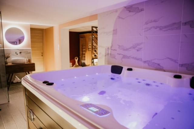uma grande banheira roxa na casa de banho em chambre d'hôte doux moment spa privatif em Maresches